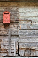 Red mailbox hung on an old wooden exterior door