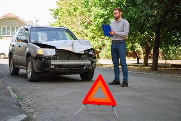 Insurer inspects car and calculates damage after car accident. Man Auto Insurance Agent Inspect vehicle damage condition. Broken car on road with Red triangle warning Stop sign