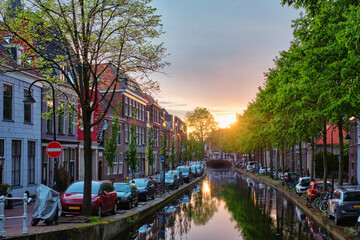 Fototapeta premium Delt canal with old houses and cars parked along on sunset