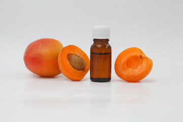 Apricot oil bottle with ripe apricots and apricot kernels isolated white