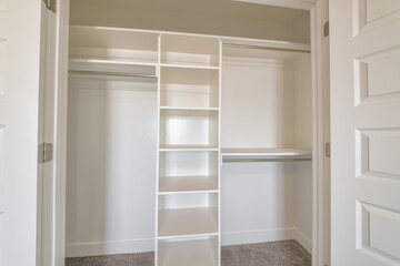 Wardrobe closet with shelves and clothes rods inside a residential house