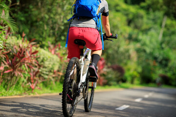 Fototapeta na wymiar Woman cycling on tropical park trail in summer
