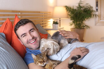 Cozy man sleeping with cat and dog 