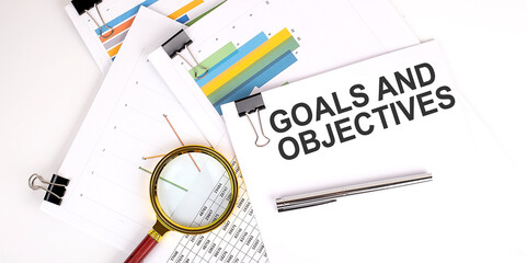 Goals and Objectives text on white paper on the light background with charts paper