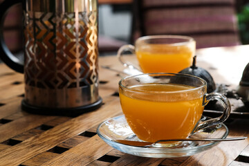 Close up view on french press and cups with sea buckthorn tea on the table.