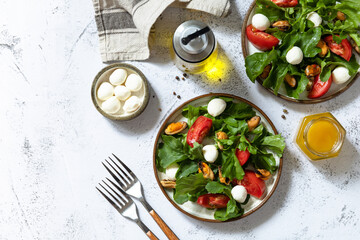 Healthy diet salad with arugula, mozzarella, mussels and vinaigrette dressing on a gray stone tabletop. Top view flat lay background. Copy space.