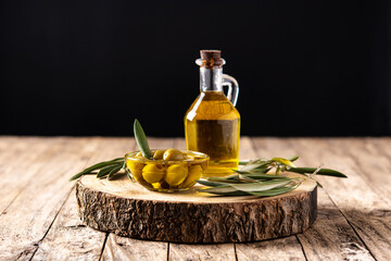 Virgin olive oil bottle and green olives on wooden table	