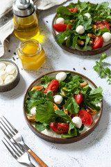 Healthy diet salad with arugula, mozzarella, mussels and vinaigrette dressing on a gray stone tabletop.