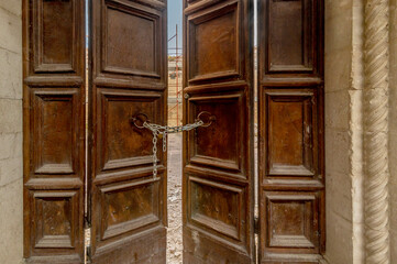 A wooden door closed by a chain with padlock at the entrance to one of the many buildings destroyed by the 2016 earthquake, Norcia, Italy