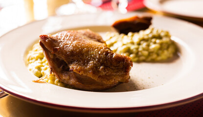 dish duck leg with green perlotto served on a white plate