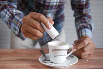 young man putting artificial sweetener in tea,