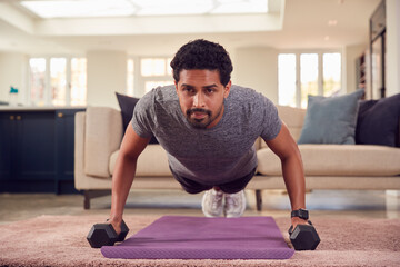 Man In Fitness Clothing At Home In Lounge Exercising With Hand Weights