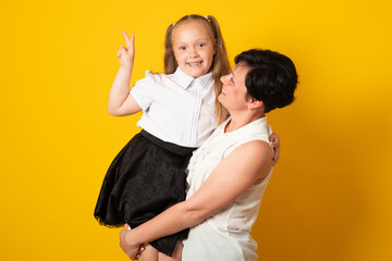 Photo of pretty young mommy hold arms hugging little daughter good mood, isolated yellow color background.