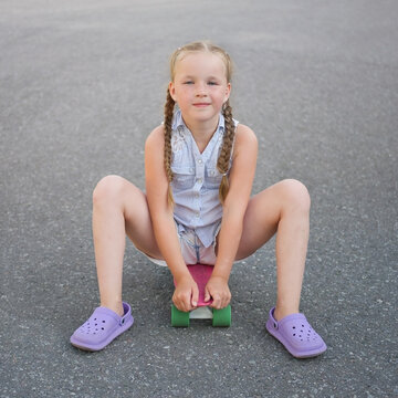 Cute little preteen girl sits on skateboard
