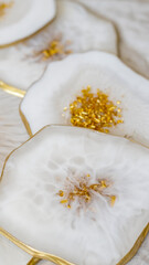 Cup holder, epoxy resin tray, stone cut, white marble with gold trim. White streaks of paint. Table setting decor, object aesthetics. Gloss, reflection. Stone effect. Blurred background. 