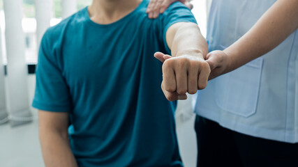 A young man with pain in the body and with a doctor helping to see and concept of physical therapy and medicine.