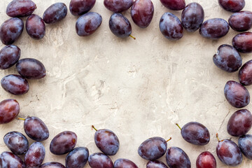 Purple plums with leaves top view. Food fruits background