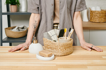 Young female standing by basket with hygiene and self-love items
