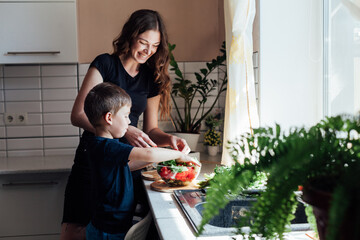 mother and son prepare a salad of vegetables in the kitchen