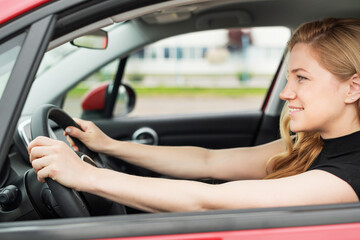 Obraz na płótnie Canvas Happy beautiful young woman drives a car.