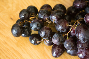 Black grapes on a table. Top view photo of fresh summer fruits. Beautiful grapes close up photo. Water drops on grape. Eating fresh concept. 