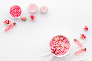 Pink roses in water with essential oil and cosmetic for spa. Top view