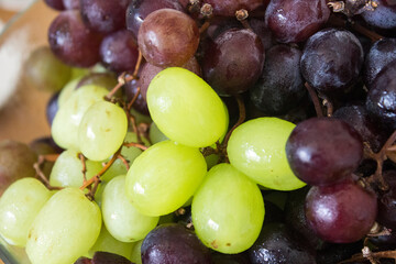 Green and black grapes close up photo. Fresh summer fruits on a table. Top view photo of beautiful berries. Fruit texture close up. Healthy eating concept. 