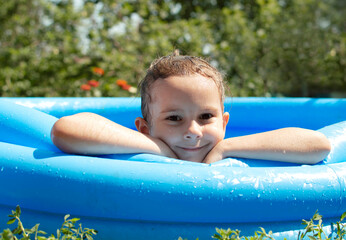 A little girl poses in front of the camera and swims in an inflatable pool in the backyard