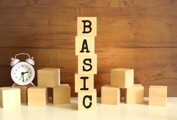 Five wooden cubes stacked vertically to form the word BASIC on a brown background.