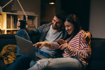couple enjoying evening at home shopping online