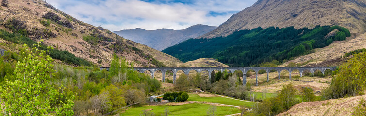 A panorama view across the railway viaduct and mountains at Glenfinnan, Scotland on a summers day