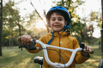 Naklejka premium portrait of little boy with his bike, outdoors in public park