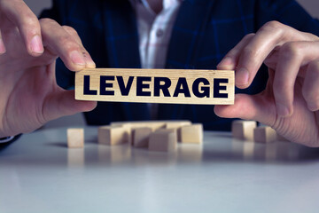 Businessman showing Leverage word in wooden block.