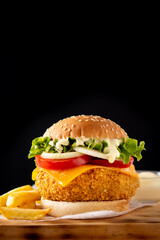 Crispy chicken burger with cheese and french fries on wooden table	