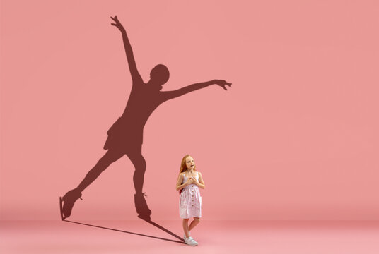 Childhood and dream about big and famous future. Conceptual image with girl and shadow of female figure skater on coral pink wall, background.