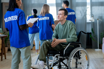 Disabled man in wheelchair talking to Asian female volunteer