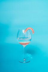 A denture in a glass of water. Dental prosthesis care. Full removable plastic denture of the jaws. Two acrylic dentures. Upper and lower jaws with fake teeth. Dentures or false teeth, close-up.