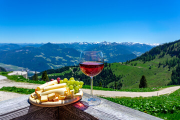 fresch tirol cheese with wine and grapes over mountain landscape