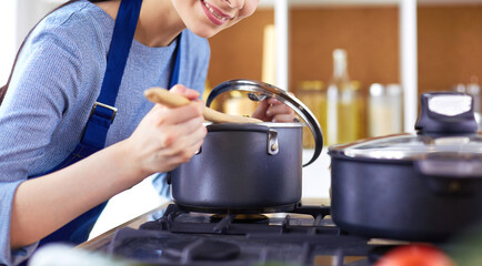 Cooking woman in kitchen with wooden spoon