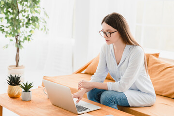Young caucasian freelancer businesswoman student tutor lecturer having online lessons, working remotely using laptop at home office, watching webinars on lockdown. E-learning concept.