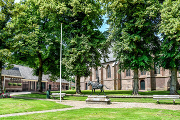 Naklejka premium In the foreground in front of the St. Nicholas Church in Dwingeloo is the statue of 'De Juffer van Batinghe', main character in the legend the architect and the damsel. Netherlands, Holland, Europe