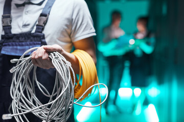 Close up of network engineer holding cables in server room during maintenance work in data center, copy space