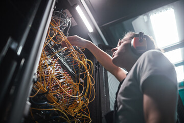 Low angle portrait of network engineer connecting cables in server room during maintenance work in data center, copy space - obrazy, fototapety, plakaty