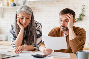 Sad disappointed mature middle-aged couple family wife and husband counting funds, savings,...