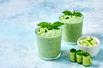 Cucumber Gazpacho - cold summer soup with basil in glasses on light background