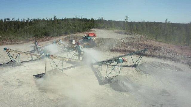 Much work is being done in the mining quarry. Drive tractors, machines engaged in filtration. A dump truck is dumping earth rock