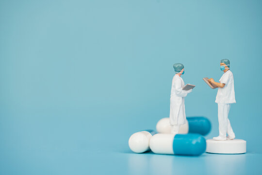 Miniature support team, Doctor emergency medical team wear surgical mask with pills and blue sea background. Health care, life insurance for covid-19 concept. Report and data science