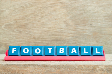 Tile alphabet letter with word football in red color rack on wood background