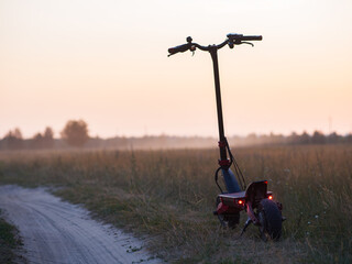 Fototapeta na wymiar Electric scooter on a sandy country road, copy space, sunrise