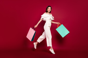 Full size profile side photo of young girl happy positive smile walk jump black friday shopping isolated over red color background